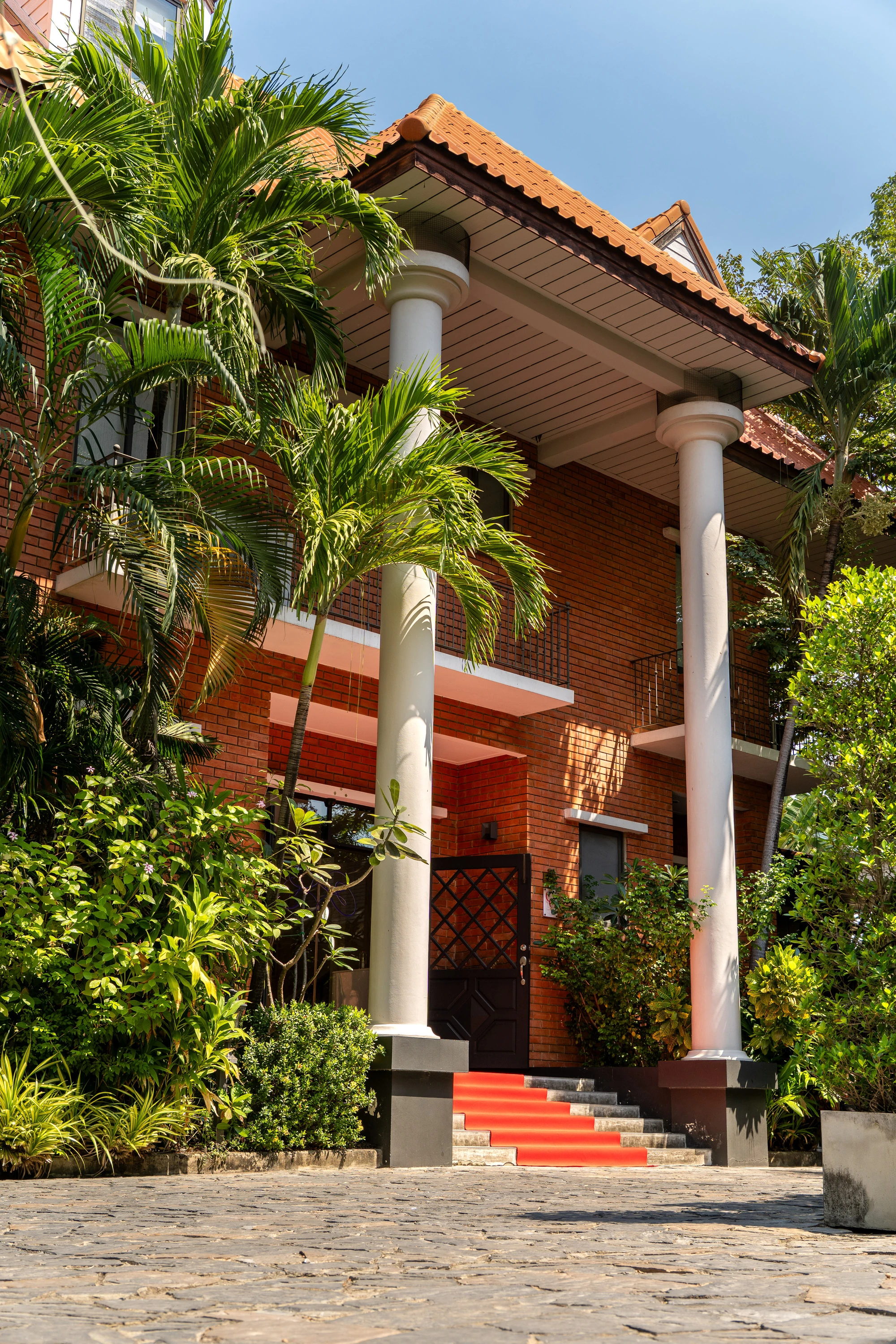 SÉREN Le Moment exterior with white columns, tropical greenery and the entrance steps
